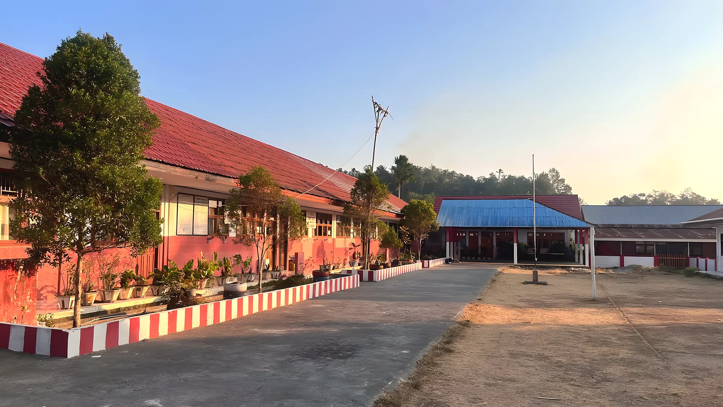 Deretan ruang kelas sekolah dengan halaman dan tiang bendera
